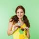 a woman in a yellow shirt is holding a pineapple