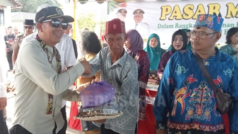 Wakil Ketua I DPRD Barito Selatan, Ideham, menyerahkan paket sembako kepada warga dalam kegiatan pasar murah di Kelurahan Mengkatip, Kecamatan Dusun Hilir. (foto: MediaSurya/dok)