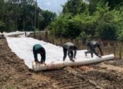 sedang memasang geotekstil secara manual Satgas TMMD Kodim 1012/Buntok Pasang Geotekstil di Desa Talio untuk Perkuat Badan Jalan