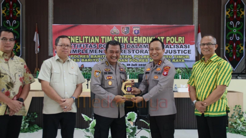 Kapolres Barito Selatan AKBP Jecson Ricsko Hutapea menyerahkan cendera mata kepada Ketua Tim STIK Lemdiklat Polri Kombes Pol Dwi Indra Maulana saat kunjungan penelitian efektivitas Polmas di wilayah DAS Barito, Jumat (25/7/2025).